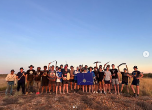 Young people holding boomerangs against blue outback sky
